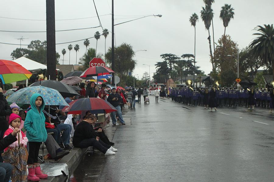 Young parade observers look on, waiting in the rain, for the final Downey Parade participants along Downey Avenue, on Dec. 3, at three in the afternoon. Despite the weather crowds of spectators turned out to watch the numerous marching bands, Latin dancers, drill teams, and other participants stride through the city. 