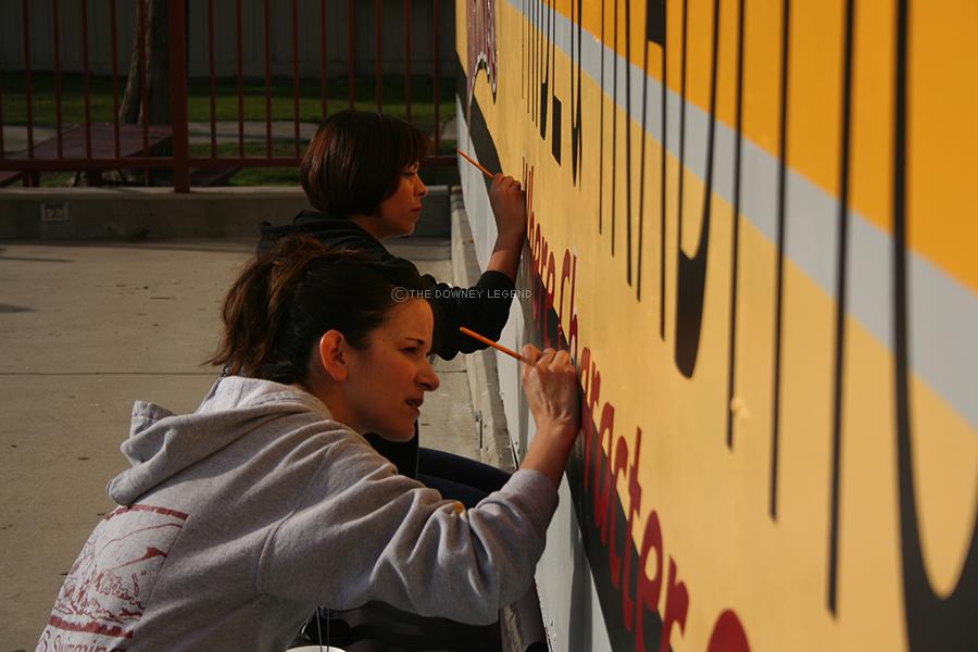 Finishing up the last part of the rally stage mural after school on Feb. 6, art teachers Ms. Puente and Ms. Carbajal-Guzman add white to emphasize the final line of “Where character counts”. Having people within the Downey community paint the rally stage saved money, rather than hiring an artist outside of Downey High School. 