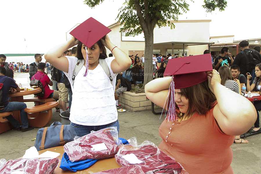 Too anxious to wait, seniors Yaritza Figueroa and Brenda Aguyo open their cap and gown packages with friends, at the lunch tables, during B lunch on, June 4, in order to try on their caps and tassel.   “ I’ve been waiting four years for this!” Figueroa said. 